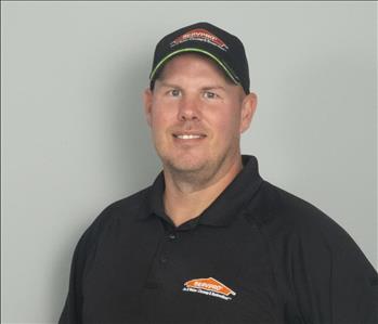 Male employee with black hat in front of gray background